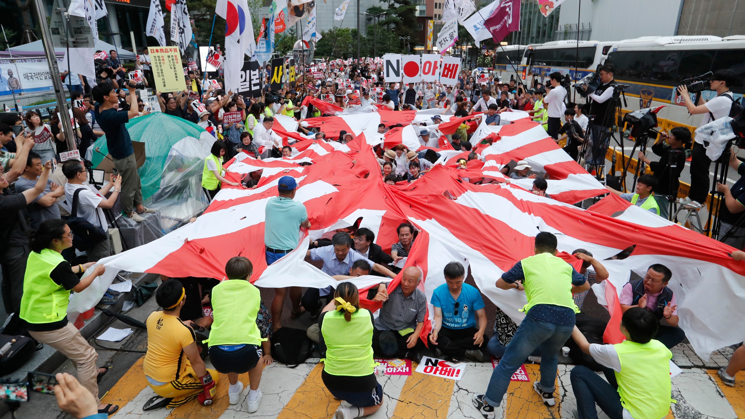 In this July 20, 2019, file photo, protesters tear a Japanese rising sun flag during a rally denouncing the Japanese government's decision on their exports to South Korea in front of Japanese Embassy in Seoul, South Korea. Japan’s “rising sun” flag is raising anger at the Olympics, with some of the host nation’s neighbors calling for it to be banned during the Tokyo Games, which start Friday, July 23, 2021. (AP Photo/Ahn Young-joon, File)