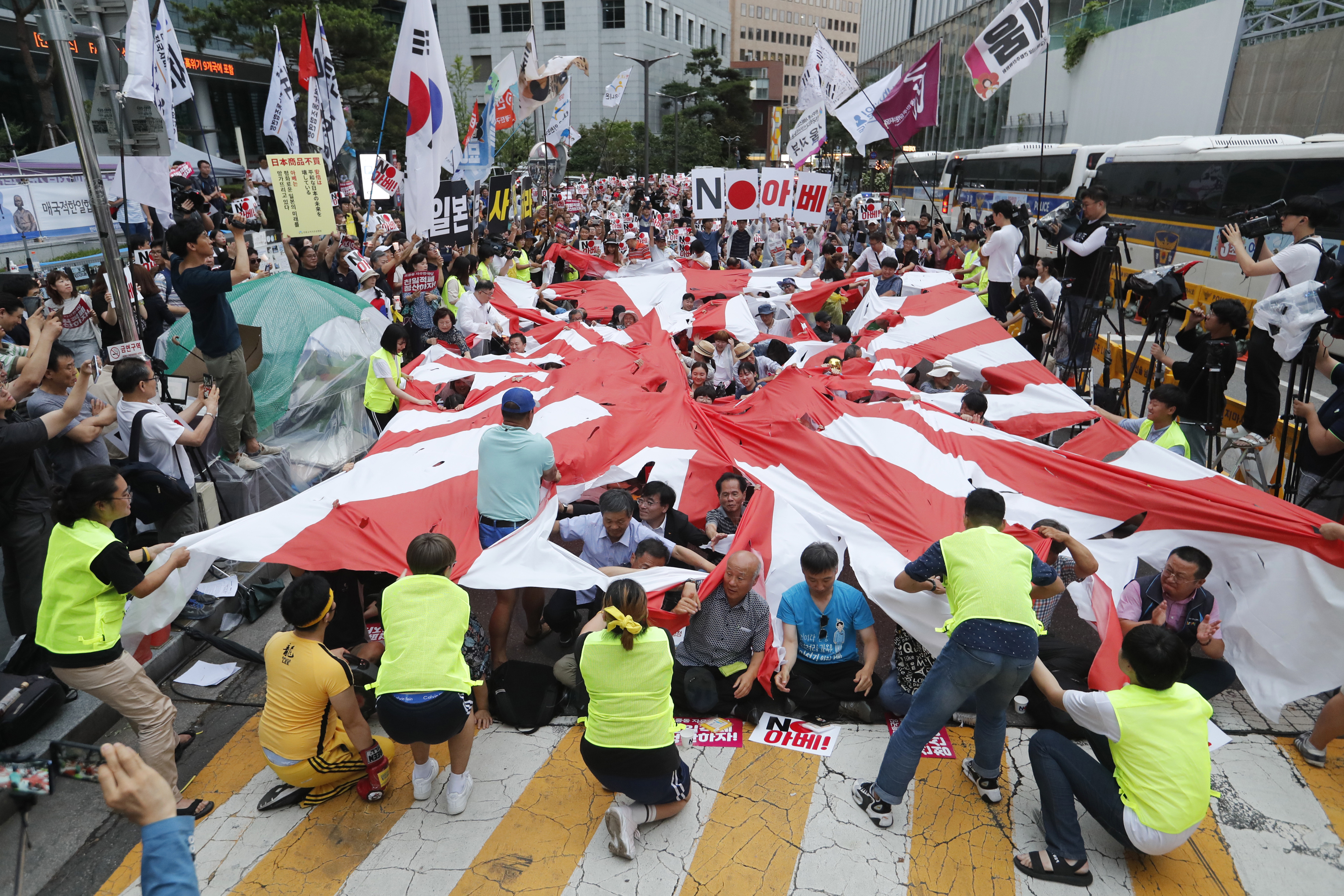 In this July 20, 2019, file photo, protesters tear a Japanese rising sun flag during a rally denouncing the Japanese government's decision on their exports to South Korea in front of Japanese Embassy in Seoul, South Korea. Japan’s “rising sun” flag is raising anger at the Olympics, with some of the host nation’s neighbors calling for it to be banned during the Tokyo Games, which start Friday, July 23, 2021. (AP Photo/Ahn Young-joon, File)