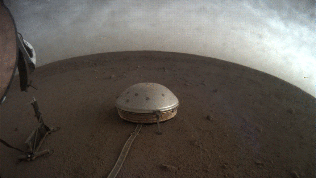 In this undated photo made available by NASA on Thursday, July 22, 2021, clouds drift over the dome-covered SEIS seismometer of the InSight lander on the surface of Mars. The quake-measuring device is providing the first detailed look at the red planet’s interior, revealing a surprisingly thin crust and a molten core. In a series of articles published in July 2021, scientists reported that the Martian crust is within the thickness range of Earth’s. Mars’ mantle, meanwhile, is roughly half that of our own much bigger planet, while the core _ measured from the dusty surface to dead center _ is more than 1,000 miles smaller. (NASA/JPL-Caltech via AP)