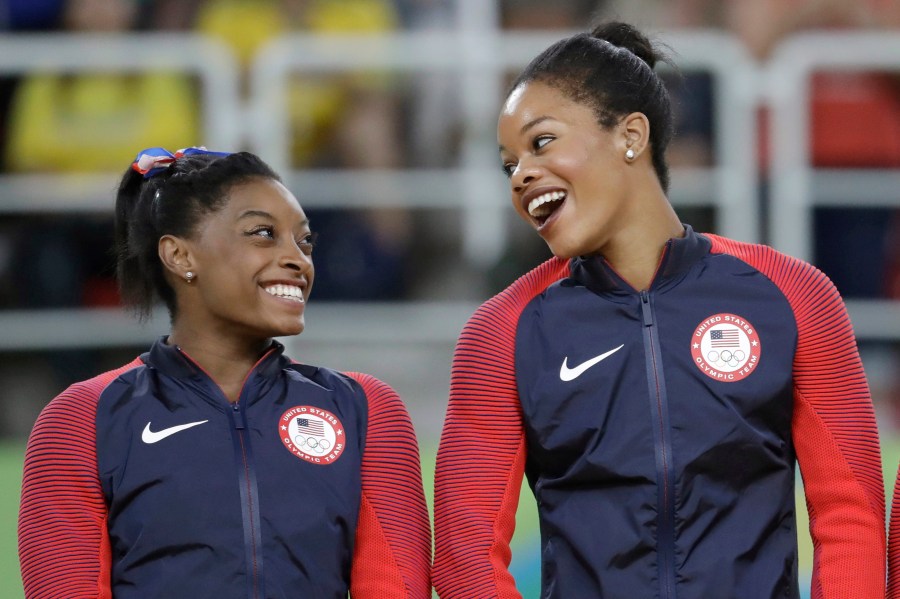 In this Aug. 9, 2016, file photo, U.S. gymnasts and gold medallists, Simone Biles, left and Gabrielle Douglas celebrate on the podium during the medal ceremony for the artistic gymnastics women's team at the 2016 Summer Olympics in Rio de Janeiro, Brazil. The success of Olympic gymnastics champions Gabby Douglas and Simone Biles has created a spike in interest in the sport in Black communities. Representation among Black girls at the upper reaches of women's gymnastics is rising. Half of the U.S. Olympic team in Tokyo are women of color. (AP Photo/Julio Cortez, File)