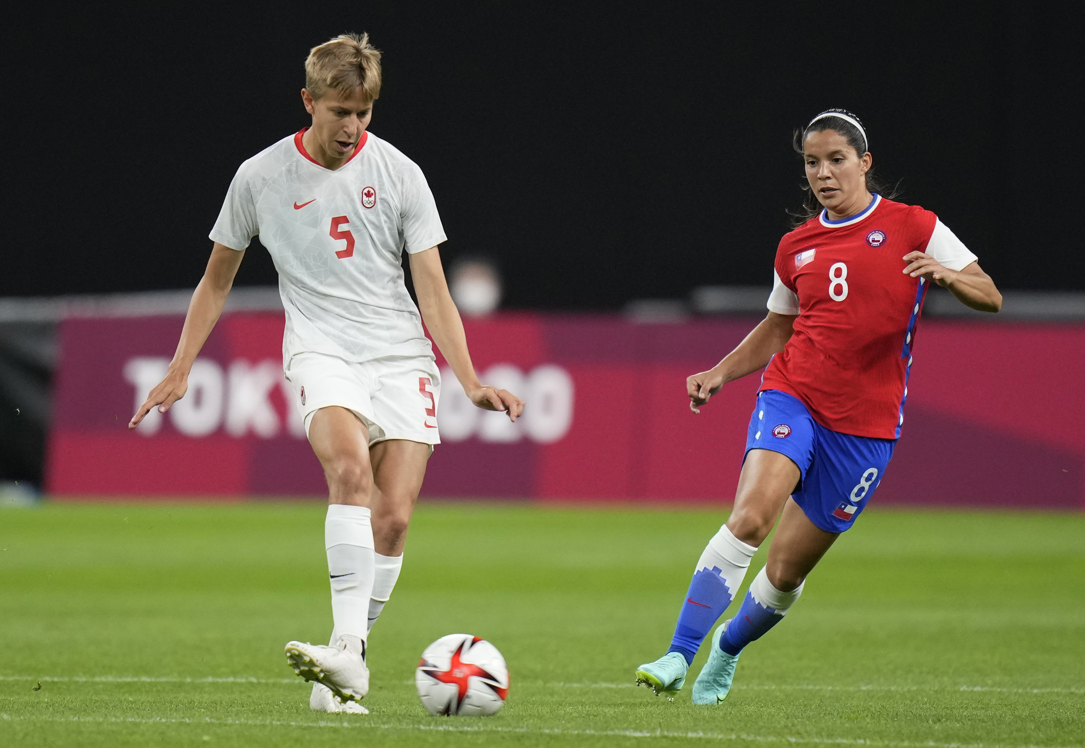 Canada's Quinn, left, and Chile's Karen Araya vie for the ball during a women's soccer match at the 2020 Summer Olympics, Saturday, July 24, 2021, in Sapporo, Japan. (AP Photo/Silvia Izquierdo)