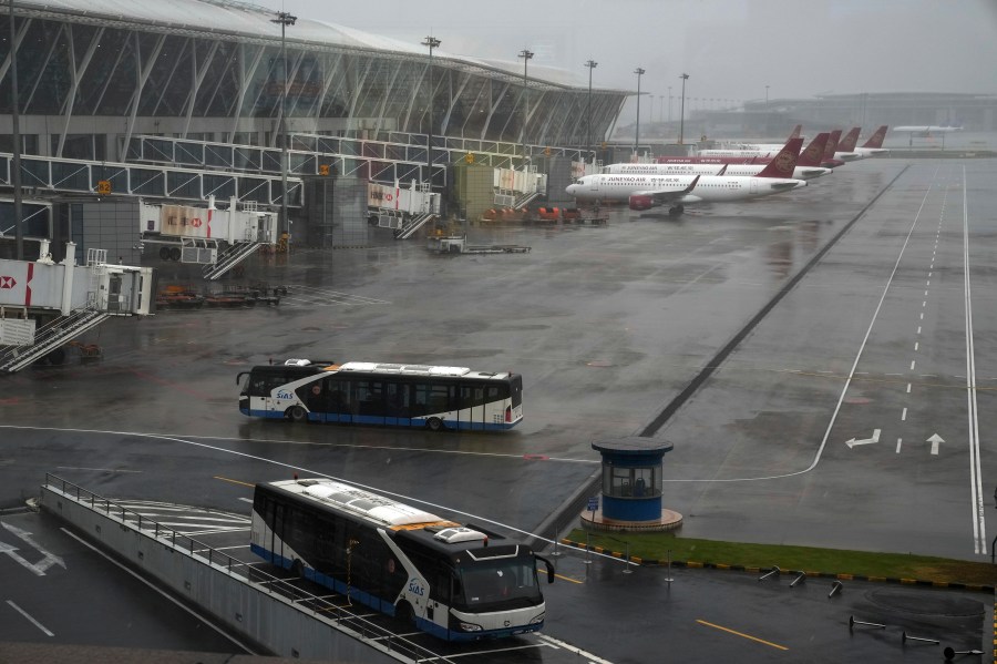 Buses and passenger airplanes are parked on the tarmac after all flights were canceled at Pudong International Airport in Shanghai, China, Sunday, July 25, 2021. (AP Photo/Andy Wong)