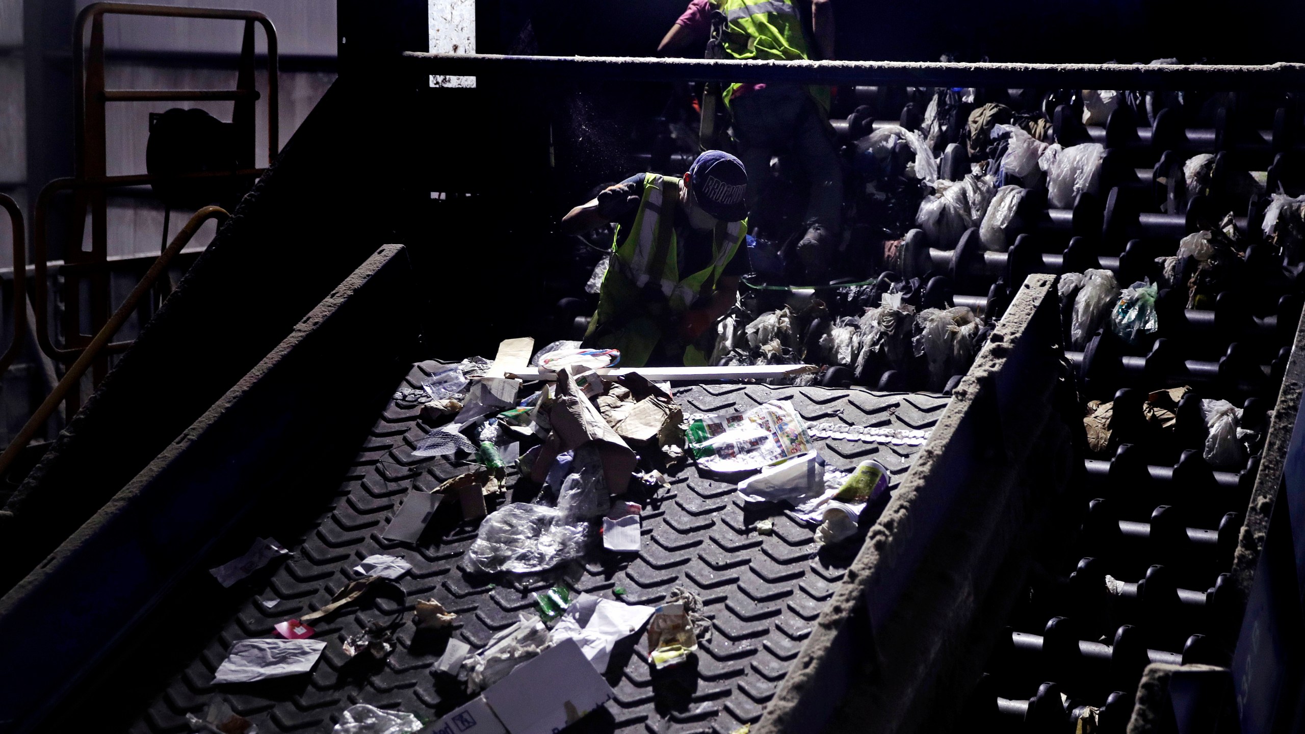 In this Thursday, Sept. 6, 2018, file photo, workers clean consumer plastic shopping bags from the clogged rollers of a machine which separates paper, plastic and metal recyclable material, in a processing building at EL Harvey & Sons, a waste and recycling company, in Westborough, Mass. (AP Photo/Charles Krupa, File)