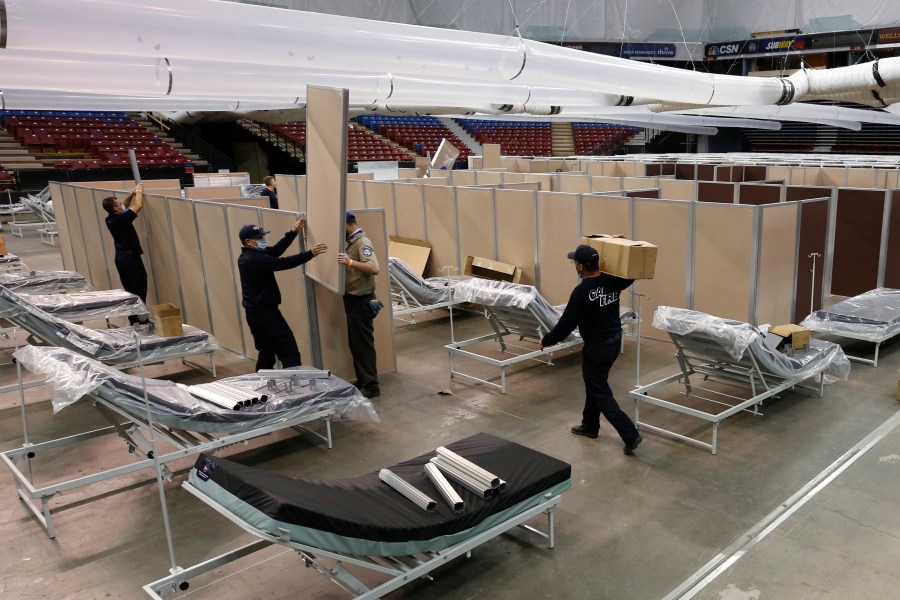 In this April 18, 2020 file photo partitions are installed between beds as work is performed to turn the Sleep Train Arena into a 400 bed emergency field hospital to help deal with the coronavirus, in Sacramento, Calif. (AP Photo/Rich Pedroncelli, File)