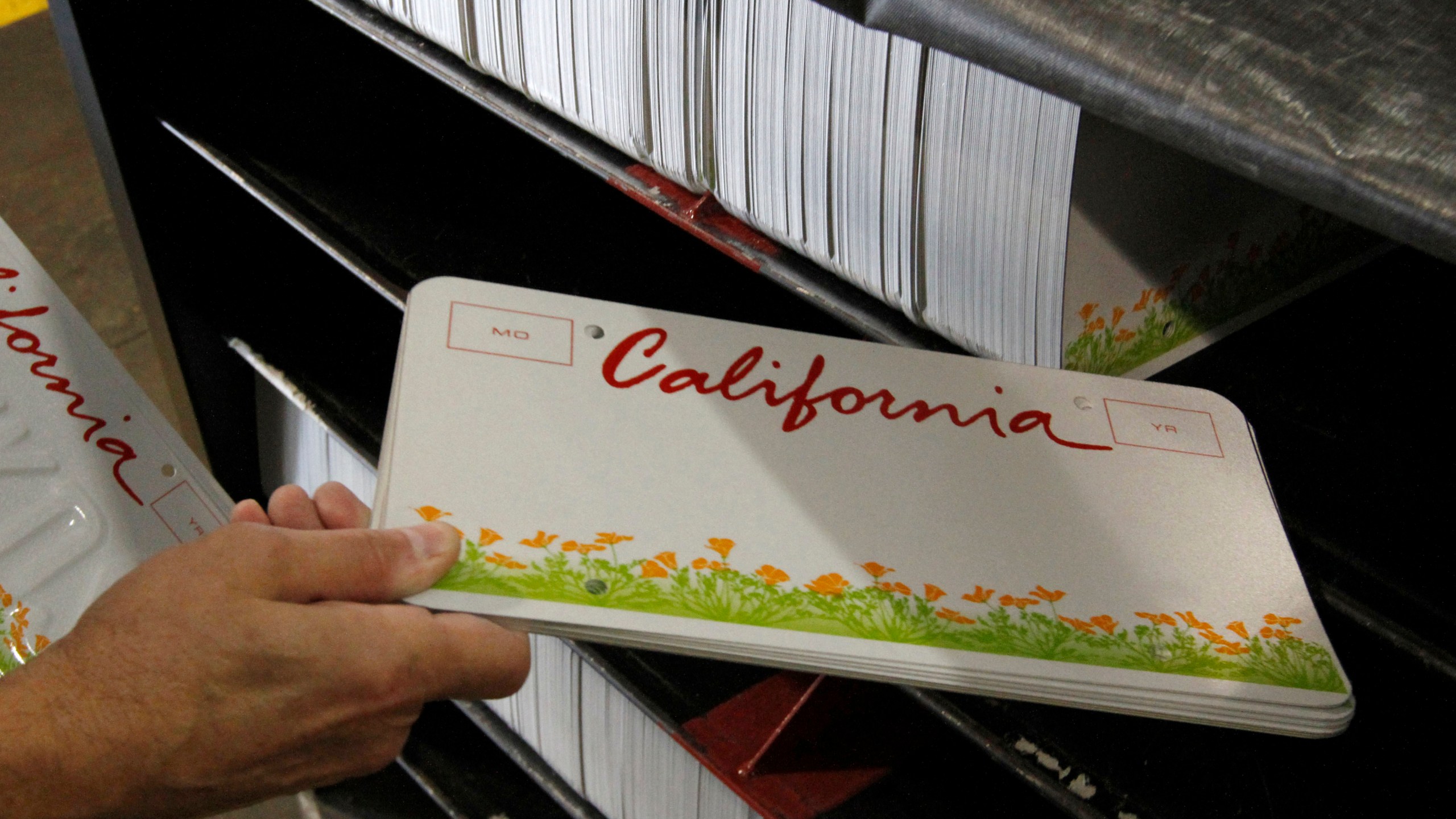 In this May 15, 2012, file photo an inmate gets some blank KIDS specialty license plates to be made through the prison industries program at Folsom State Prison. (Rich Pedroncelli/Associated Press)