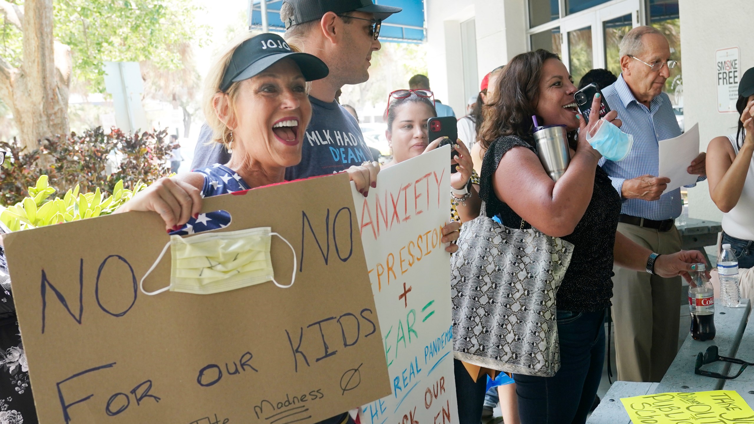 Joann Marcus of Fort Lauderdale, left, cheers as she listens to the Broward School Board's emergency meeting, Wednesday, July 28, 2021, in Fort Lauderdale, Fla. (AP Photo/Marta Lavandier)