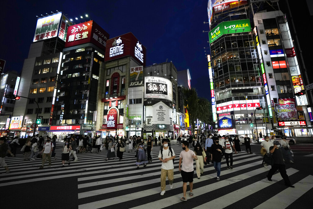 People walk along a pedestrian crossing Friday, July 30, 2021, in Tokyo, as Japanese Prime Minister Yoshihide Suga expanded a coronavirus state of emergency to four more areas in addition to Tokyo following record spikes in infections as the capital hosts the Olympics. (AP Photo/Eugene Hoshiko)