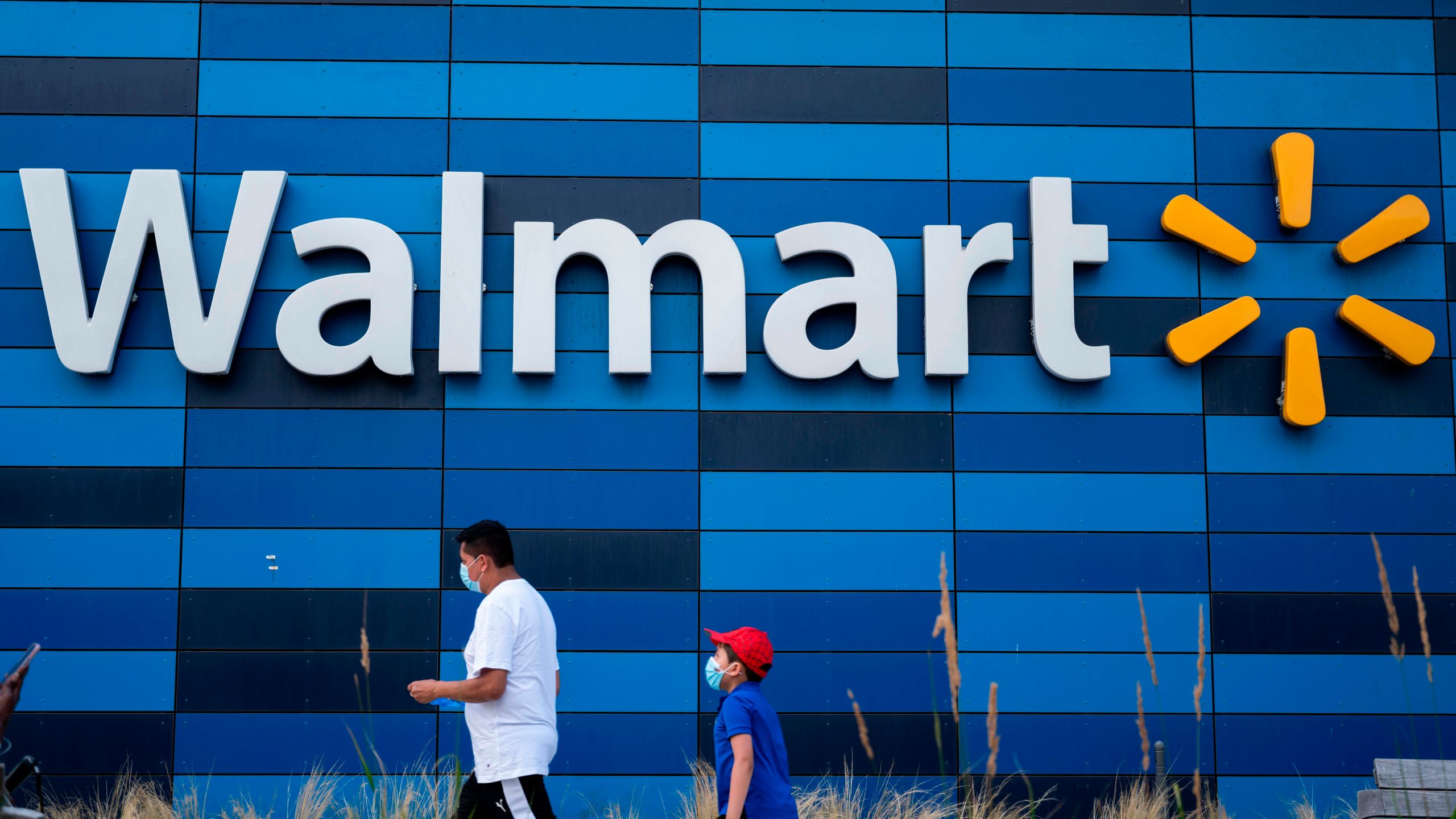 A man and child wearing facemasks walk in front of a Walmart store in Washington, DC on July 15, 2020. (ANDREW CABALLERO-REYNOLDS/AFP via Getty Images)