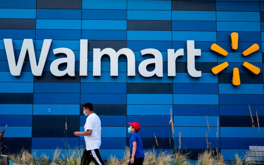 A man and child wearing facemasks walk in front of a Walmart store in Washington, DC on July 15, 2020. (ANDREW CABALLERO-REYNOLDS/AFP via Getty Images)