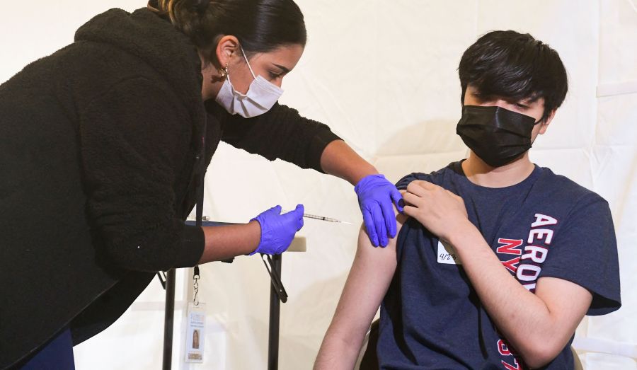 Anthony Briseno, 20, receives his first Pfizer COVID-19 vaccine administered Medical Assistant Karina Cisneros from St. John's Well Child and Family Center at Abraham Lincoln High School in Los Angeles on April 23, 2021. (FREDERIC J. BROWN/AFP via Getty Images)