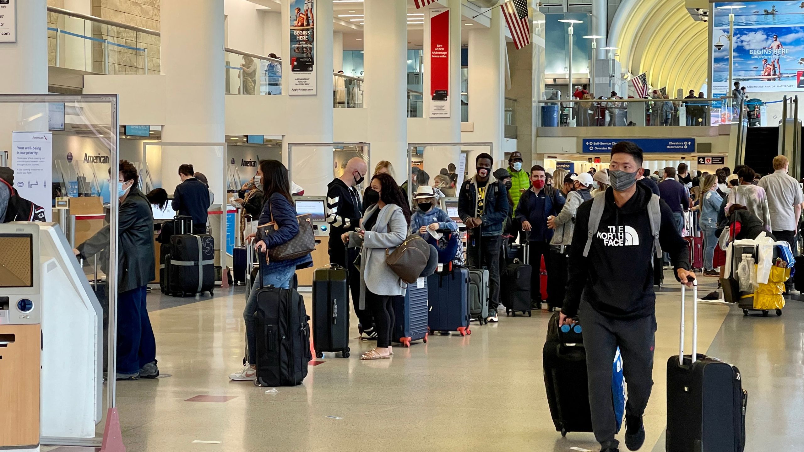 Passengers wait in line at the American Airlines checkin counters at the Los Angeles International Airport (LAX) on April 24, 2021. (DANIEL SLIM/AFP via Getty Images)