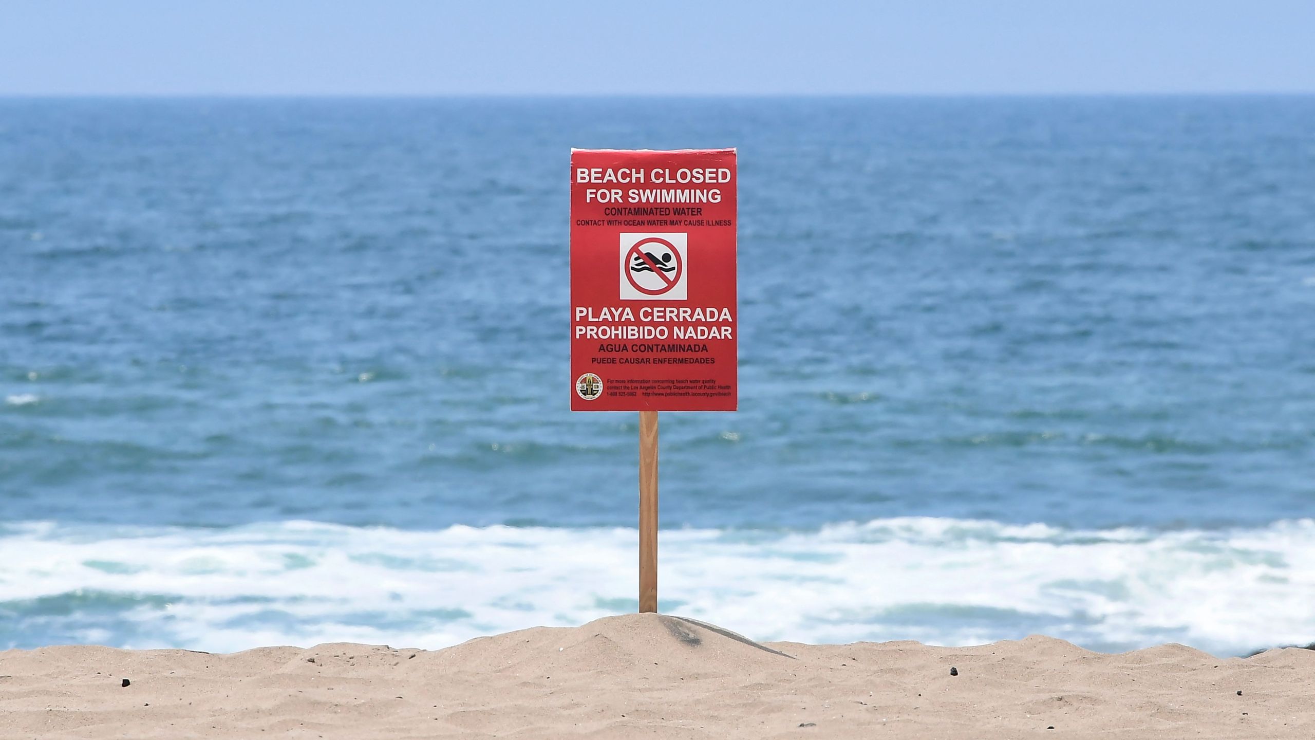 A sign indicates that the Dockweiler State Beach is closed to swimming after a sewage spill in Playa del Rey, in Los Angeles County, California, on July 13, 2021. (FREDERIC J. BROWN/AFP via Getty Images)