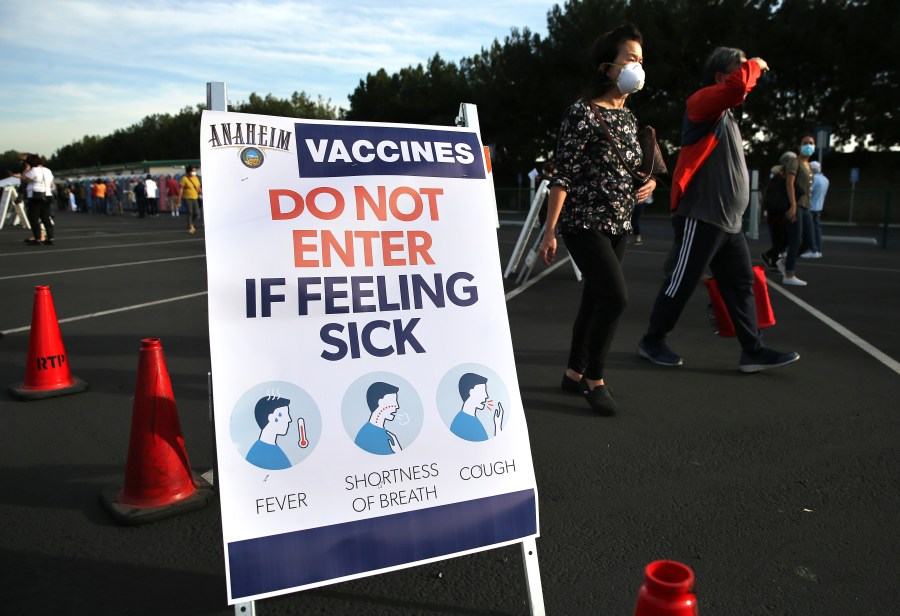 People walk at a mass COVID-19 vaccination site in a parking lot for Disneyland Resort on Jan. 13, 2021 in Anaheim. (Mario Tama/Getty Images)