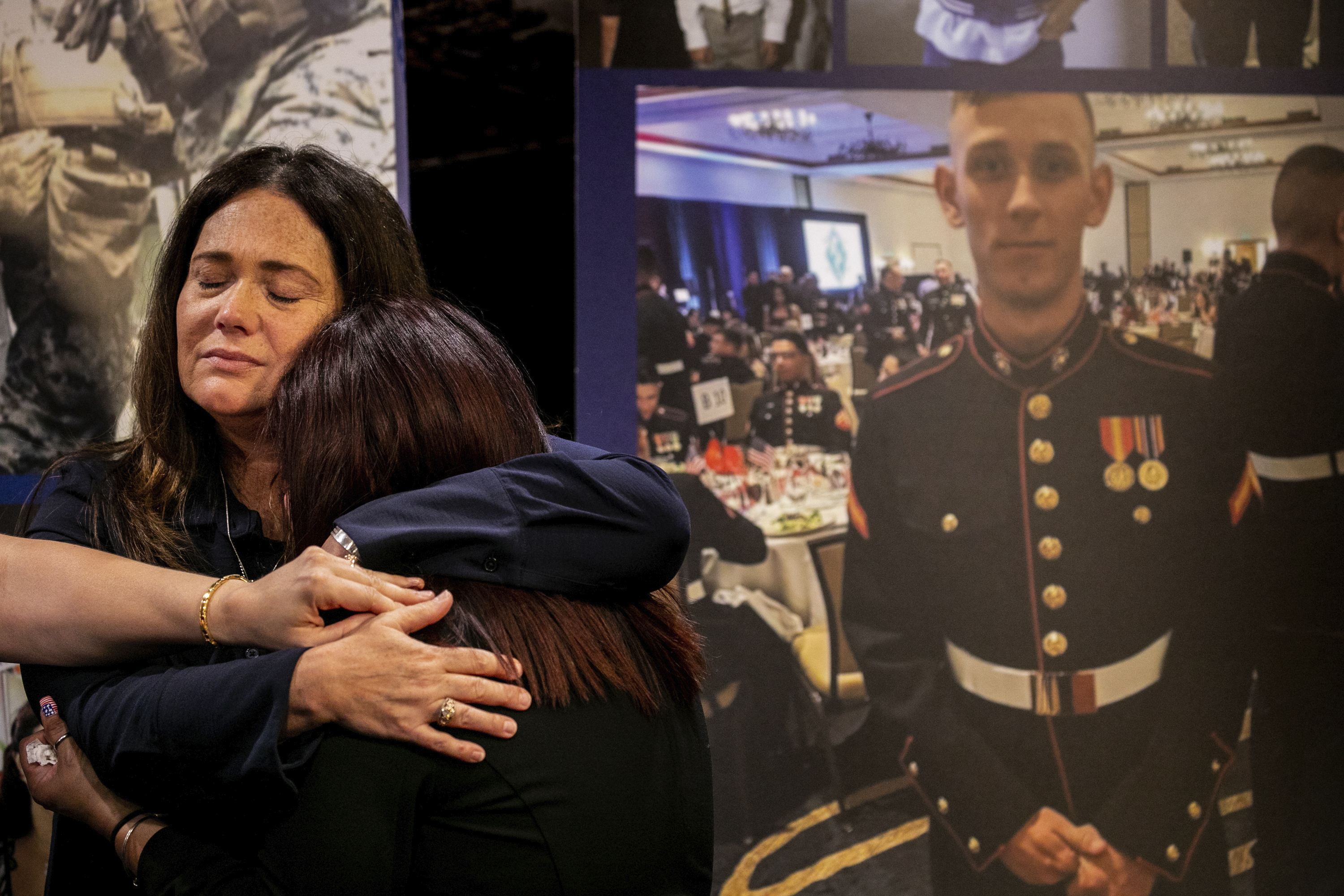 Christiana Sweetwood, mother of Marine Lance Corporal Chase Sweetwood, hand coming from left, Aleta Bath, mother of Private First Class Evan Bath and Lupita Garcia, mother of Marine Lance Corporal Marco Barranco embrace each other at a press conference next to a picture of Chase Sweetwood July 29, 2021, in Oceanside, Calif. (Sam Hodgson/The San Diego Union-Tribune via AP)