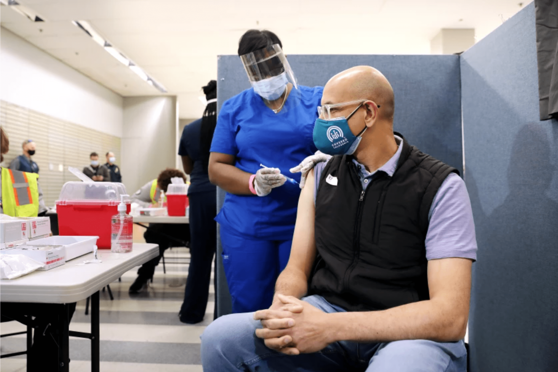 Dr. Mark Ghaly, secretary of the California Health and Human Services Agency, gets a one-dose Johnson & Johnson COVID-19 vaccination by nurse LeShay Brown at the Baldwin Hills Crenshaw Plaza in Los Angeles in March.(Christina House / Los Angeles Times)