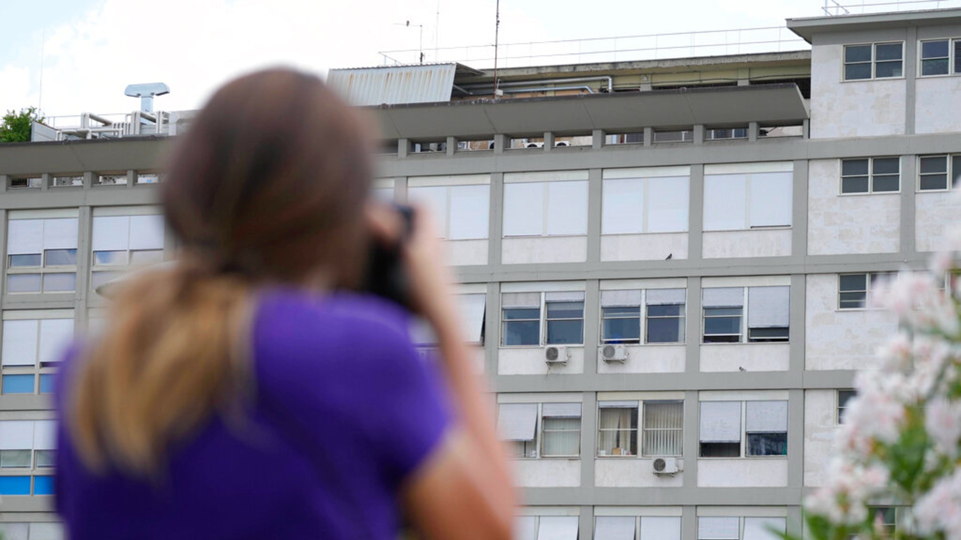 A press photographer aims her lens at the 10th floor of the Agostino Gemelli hospital, where Pope Francis was hospitalized Sunday, in Rome, Friday, July 9, 2021. (AP Photo/Gregorio Borgia)