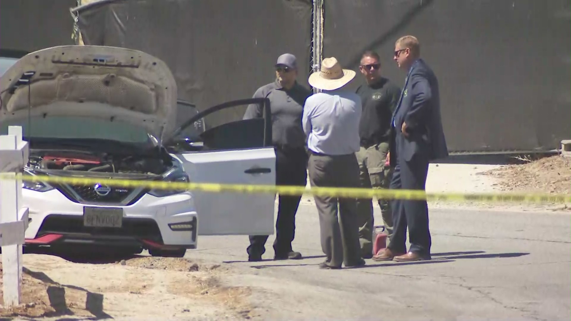 Law enforcement stand outside a car where a woman was found dead in La Habra Heights July 5, 2021. (KTLA)