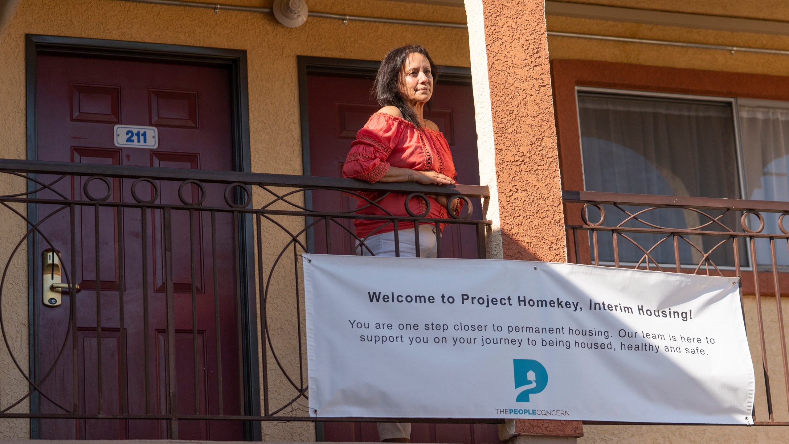 In this Wednesday, June 30, 2021, photo Veronica Perez poses outside her new home at the Mollie Mason Project Homekey site in Los Angeles. (AP Photo/Damian Dovarganes)