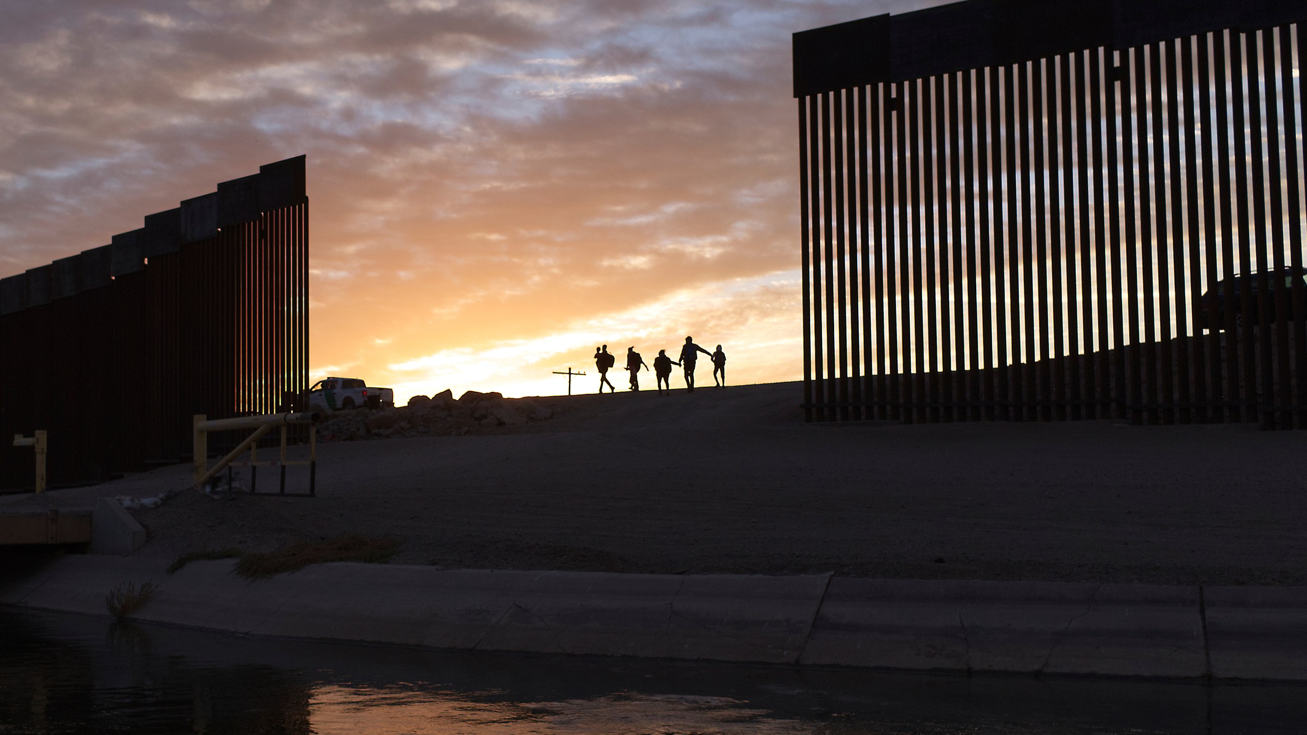 In this June 10, 2021, file photo, a pair of migrant families from Brazil pass through a gap in the border wall to reach the United States after crossing from Mexico to Yuma, Ariz., to seek asylum. (AP Photo/Eugene Garcia, File)