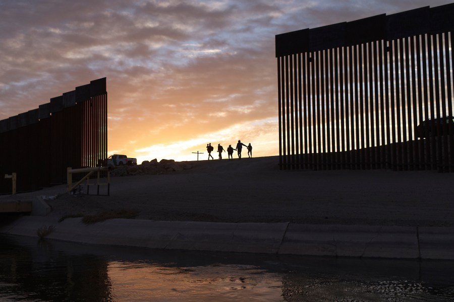 In this June 10, 2021, file photo, a pair of migrant families from Brazil pass through a gap in the border wall to reach the United States after crossing from Mexico to Yuma, Ariz., to seek asylum. (AP Photo/Eugene Garcia, File)