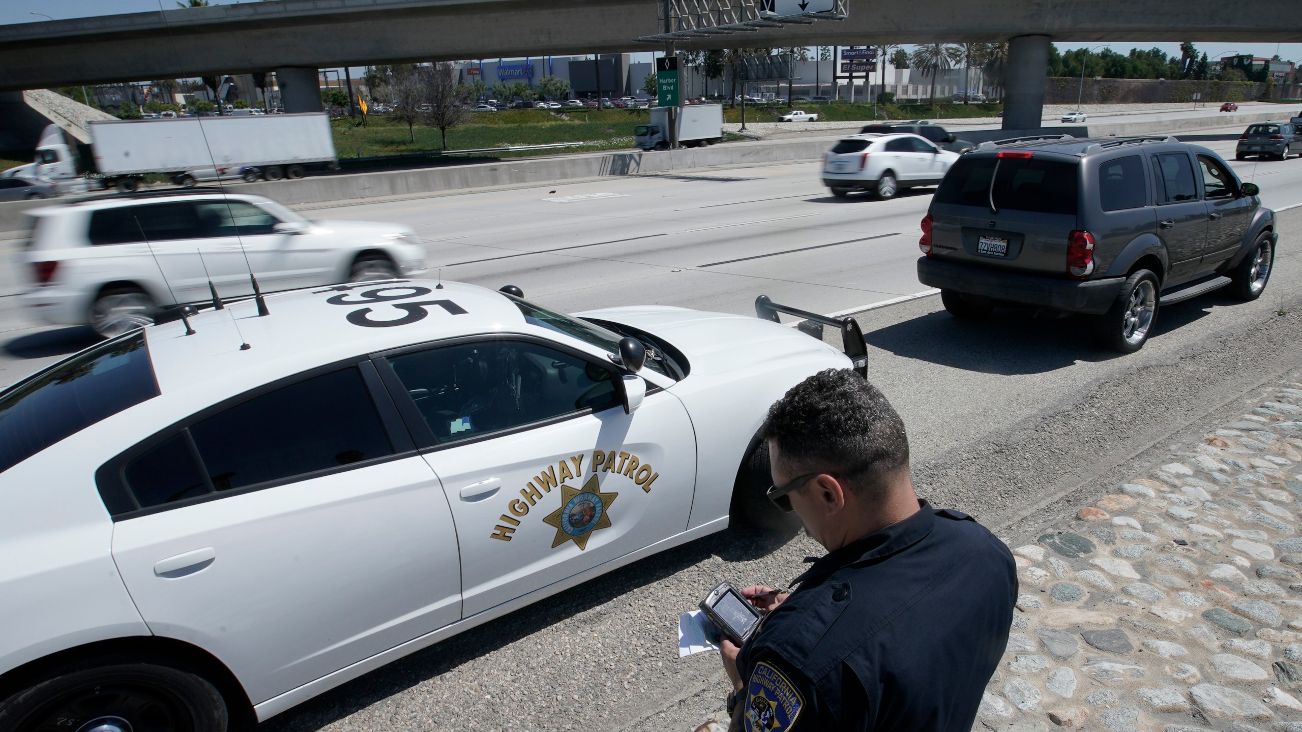 In this April 23, 2021 file photo, California Highway Patrol officer Troy Christensen runs a driver's license after stopping a motorist along Interstate 5 who was suspected of speeding in Anaheim, Calif. (AP Photo/Chris Carlson)