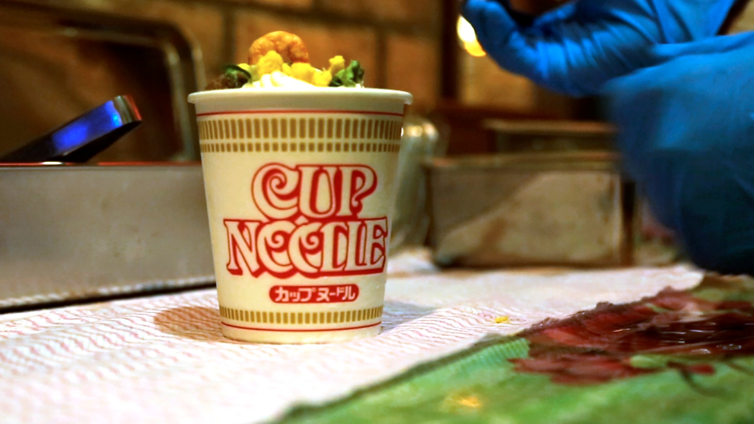 A Cup Noodle ice cream, made with the powdered soup of Cup Noodle and topped with freeze-fried shrimp, onions, egg and meat, is prepared to be eaten at the Cup Noodles Museum in Yokohama, Japan, on Friday, Aug. 6, 2021. Sold only at the Yokohama museum, the ice cream embodies a spirit of adventure in Japanese foods. (AP Photo/John Leicester)