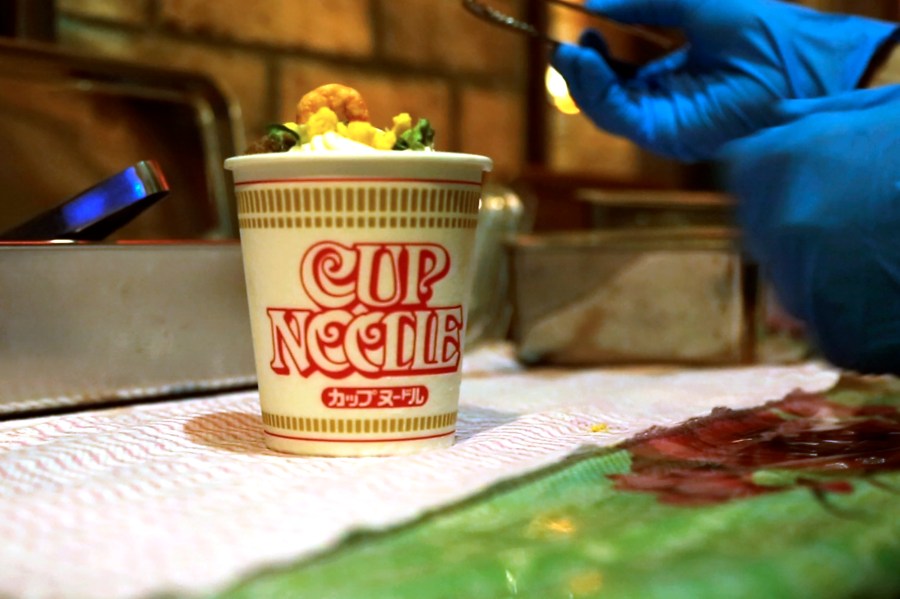 A Cup Noodle ice cream, made with the powdered soup of Cup Noodle and topped with freeze-fried shrimp, onions, egg and meat, is prepared to be eaten at the Cup Noodles Museum in Yokohama, Japan, on Friday, Aug. 6, 2021. Sold only at the Yokohama museum, the ice cream embodies a spirit of adventure in Japanese foods. (AP Photo/John Leicester)