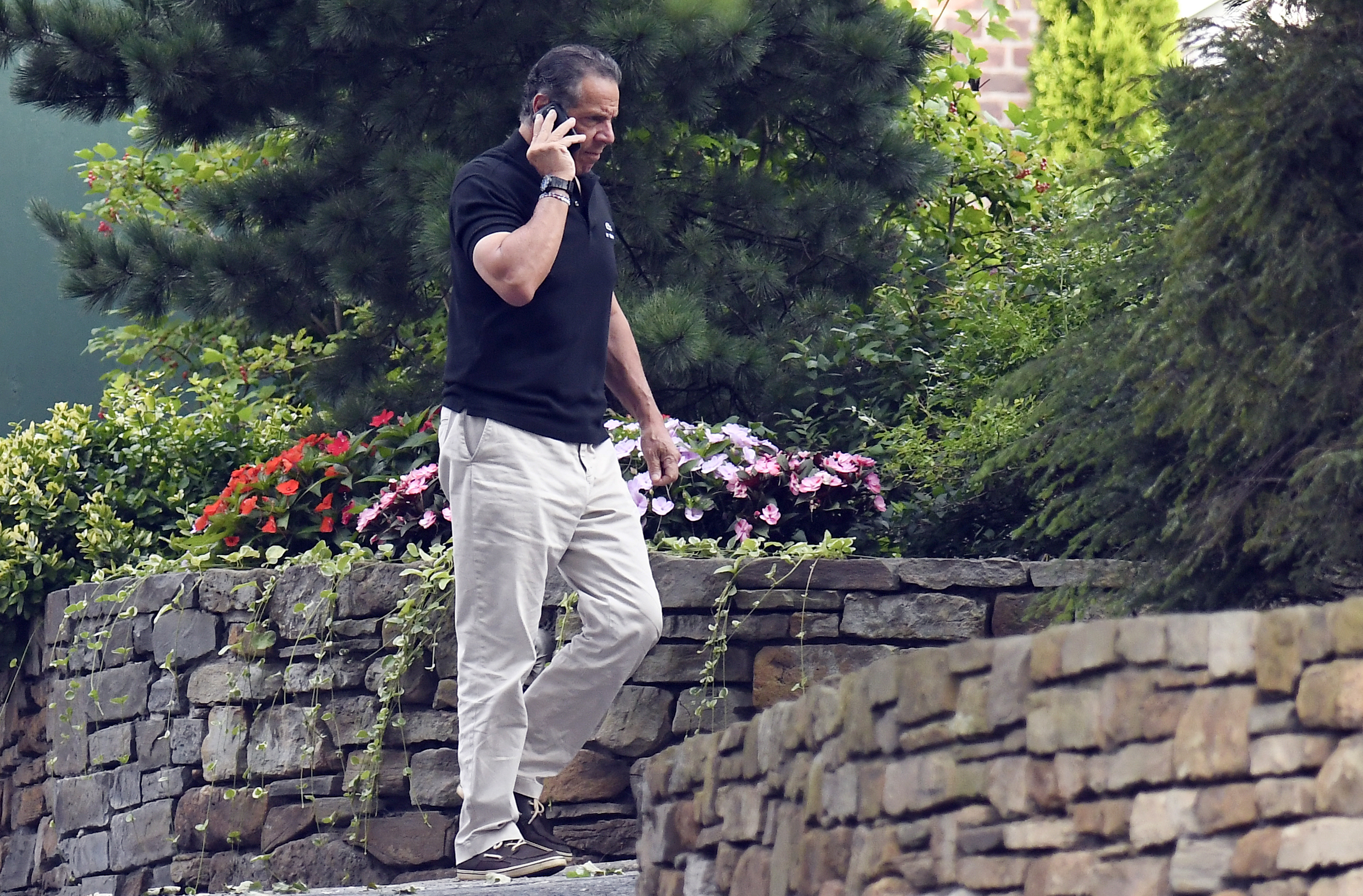 Gov. Andrew Cuomo talks on the phone while walking with his dog Captain at the New York state Executive Mansion, Saturday, Aug. 7, 2021, in Albany, N.Y. (AP Photo/Hans Pennink)