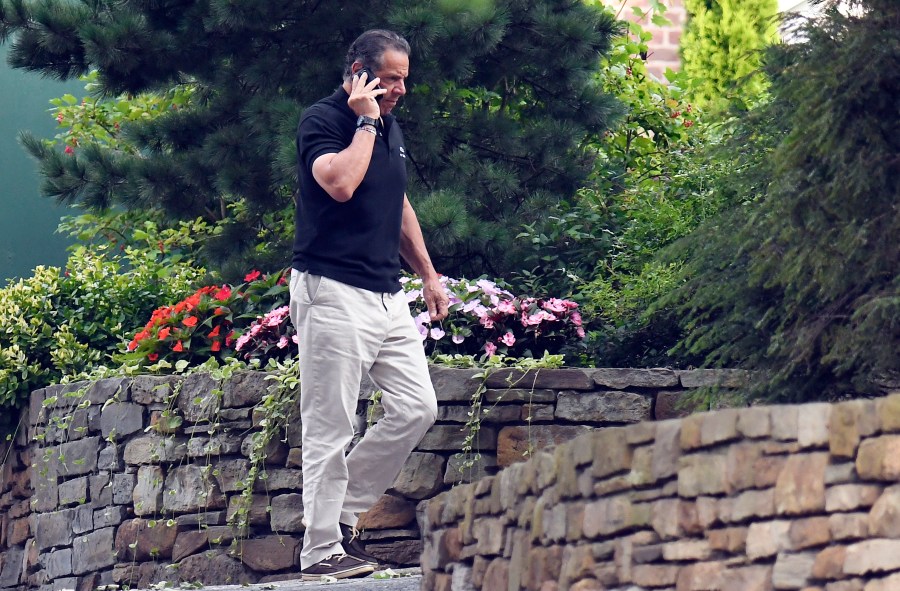 Gov. Andrew Cuomo talks on the phone while walking with his dog Captain at the New York state Executive Mansion, Saturday, Aug. 7, 2021, in Albany, N.Y. (AP Photo/Hans Pennink)