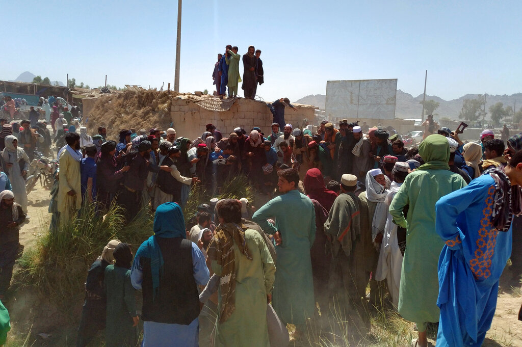 Taliban fighters and Afghans gather around the body of a member of the security forces who was killed, inside the city of Farah, capital of Farah province, southwest Afghanistan, Wednesday, Aug. 11, 2021. (AP Photo/Mohammad Asif Khan)