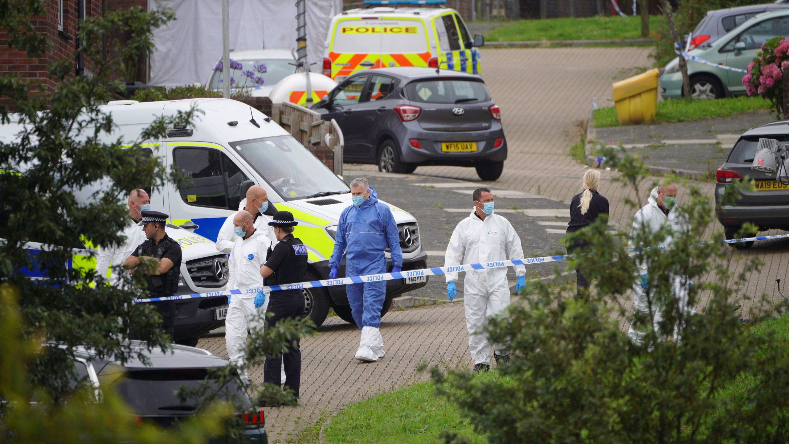 Forensic officers walk in Biddick Drive in the Keyham area of Plymouth, England Friday Aug. 13, 2021 where six people were killed in a shooting incident. (Ben Birchall/PA via AP)