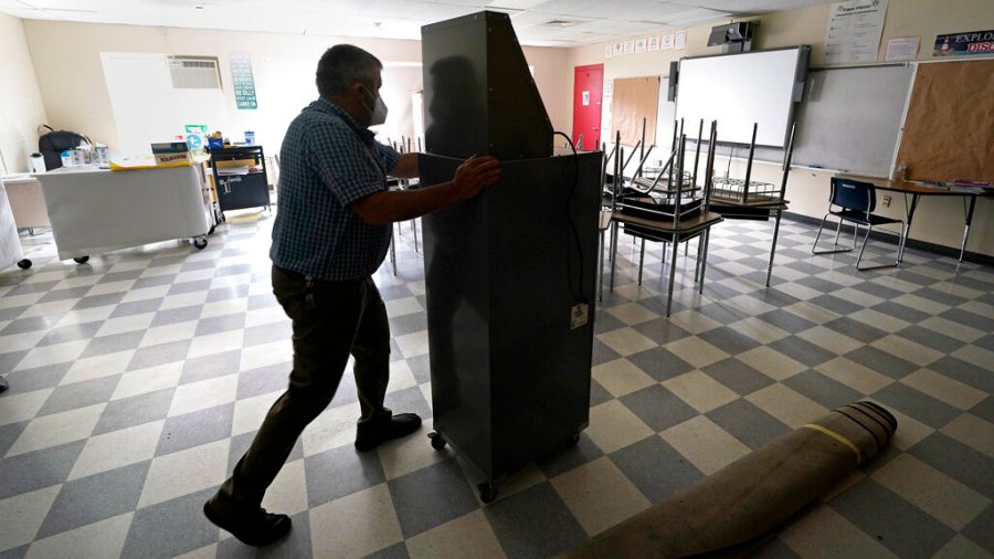 Whitney Anderson wheels a recently purchased air scrubber through a classroom in advance of the school year at the E.N. White School in Holyoke, Mass., on Wednesday, Aug. 4, 2021. (AP Photo/Charles Krupa)