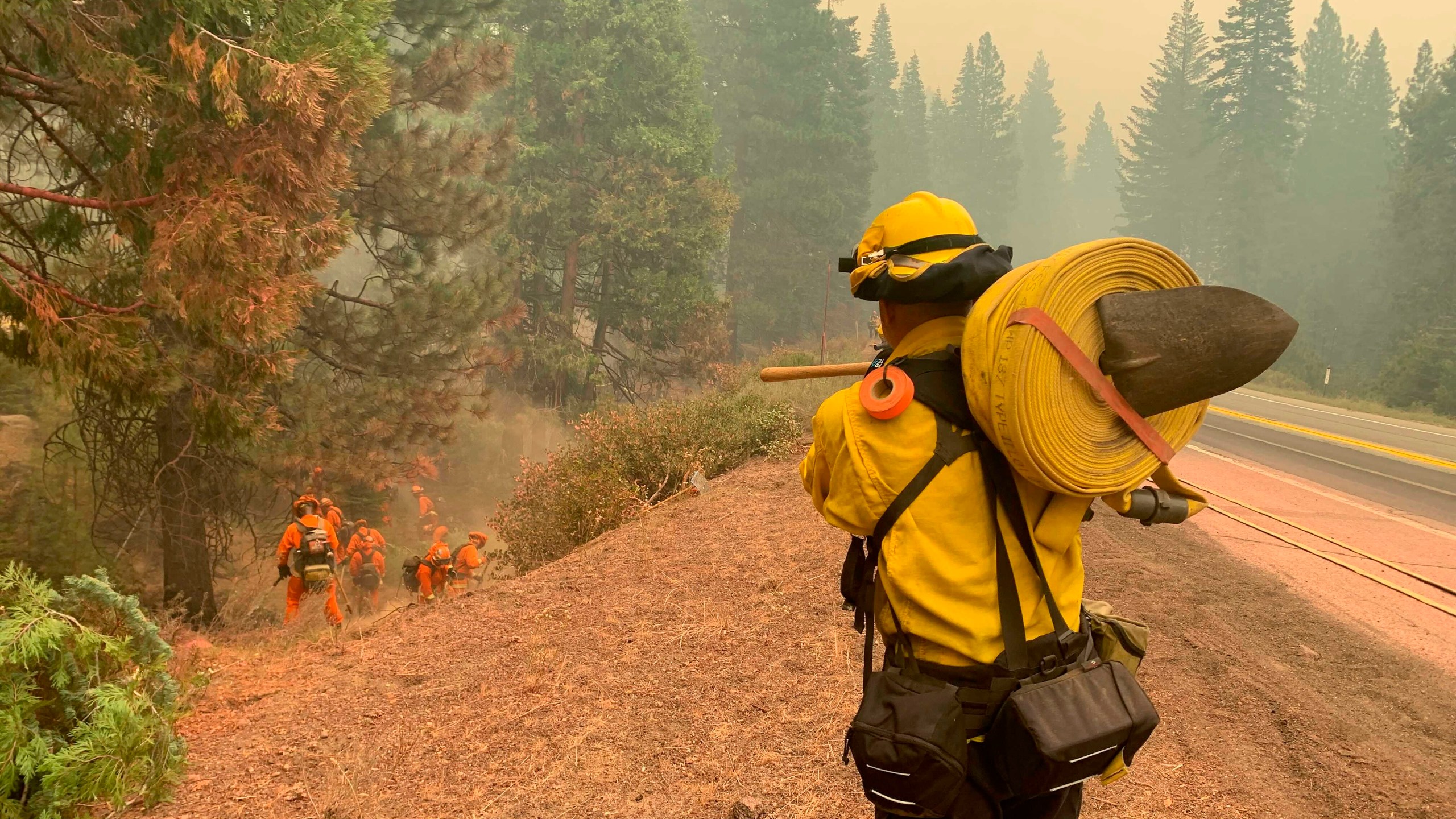 CalFire firefighters and California Correctional Center (CCC) inmates fight a spot fire on the side of Highway CA-36 between Chester and Westwood in Plumas County, Calif., Friday, Aug. 13, 2021. In California, the Dixie Fire that virtually destroyed the Sierra Nevada town of Greenville is less than a third surrounded. Fire officials say Northern California will have dangerous fire weather on Friday, including possible lightning that could spark more blazes.(AP Photo/Eugene Garcia)