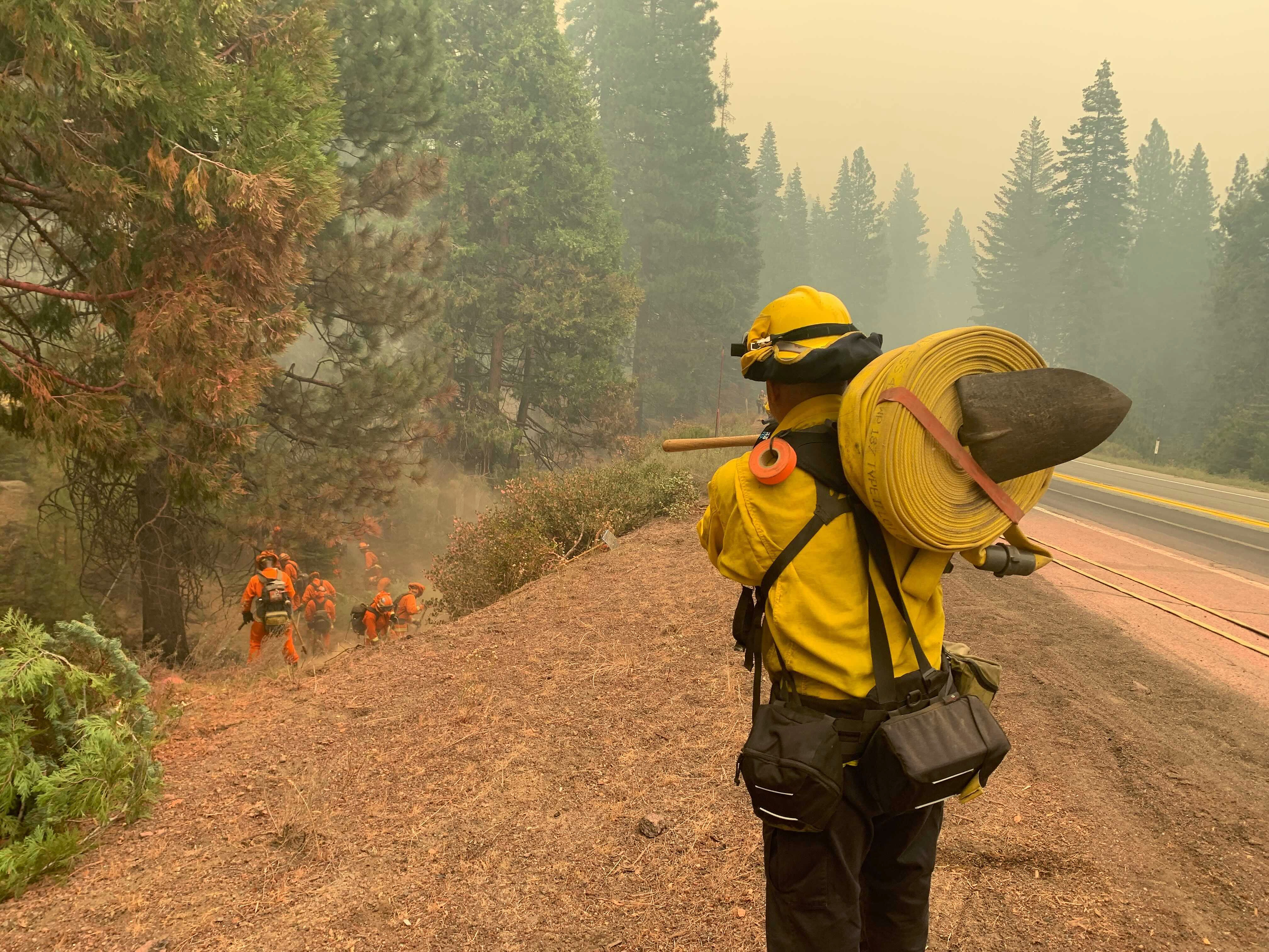 CalFire firefighters and California Correctional Center (CCC) inmates fight a spot fire on the side of Highway CA-36 between Chester and Westwood in Plumas County, Calif., Friday, Aug. 13, 2021. In California, the Dixie Fire that virtually destroyed the Sierra Nevada town of Greenville is less than a third surrounded. Fire officials say Northern California will have dangerous fire weather on Friday, including possible lightning that could spark more blazes.(AP Photo/Eugene Garcia)