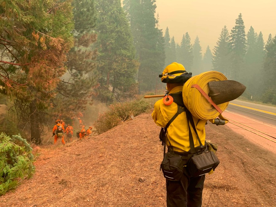 CalFire firefighters and California Correctional Center (CCC) inmates fight a spot fire on the side of Highway CA-36 between Chester and Westwood in Plumas County, Calif., Friday, Aug. 13, 2021. In California, the Dixie Fire that virtually destroyed the Sierra Nevada town of Greenville is less than a third surrounded. Fire officials say Northern California will have dangerous fire weather on Friday, including possible lightning that could spark more blazes.(AP Photo/Eugene Garcia)