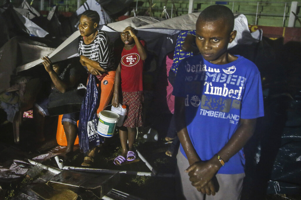 People affected by the Saturday's earthquake take cover from the rain of Tropical Depression Grace at a refugee camp in Les Cayes, Haiti, Monday, Aug. 16, 2021. (AP Photo/Joseph Odelyn)