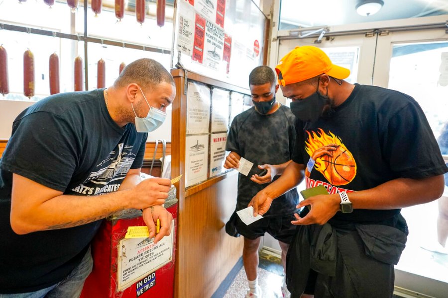 A Katz's Deli employee, left, checks the proof of vaccination from customers who will be eating inside the restaurant, Tuesday, Aug. 17, 2021, in New York. (AP Photo/Mary Altaffer)