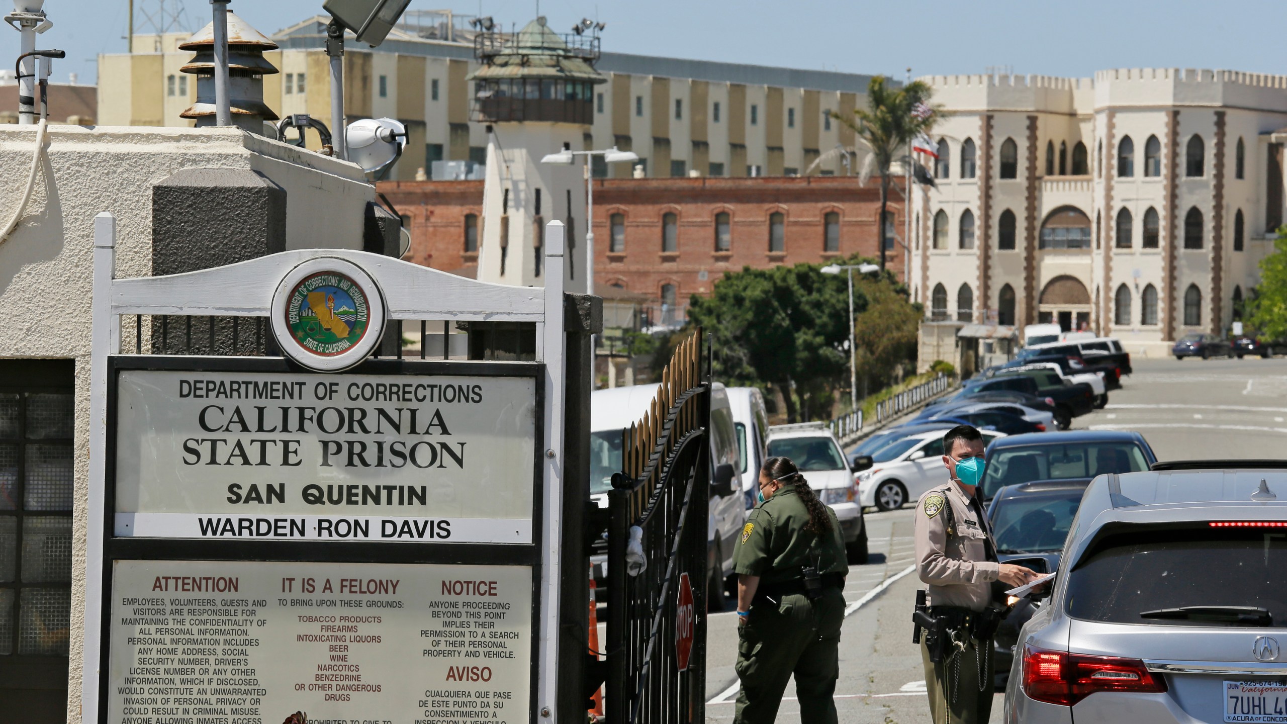 In this July 9, 2020 file photo a correctional officer checks a car entering the main gate of San Quentin State Prison, in San Quentin, Calif. (AP Photo/Eric Risberg,File)