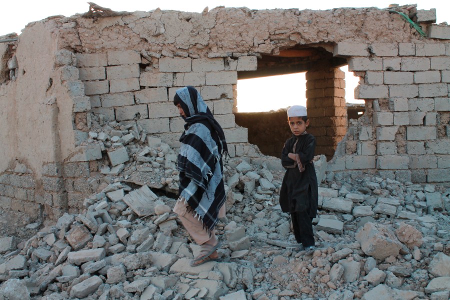 Afghan boys walk near a damaged house after airstrikes in two weeks ago during a fight between government forces and the Taliban in Lashkar Gah, Helmand province, southwestern, Afghanistan, Saturday, Aug. 21, 2021. (AP Photo/Abdul Khaliq)