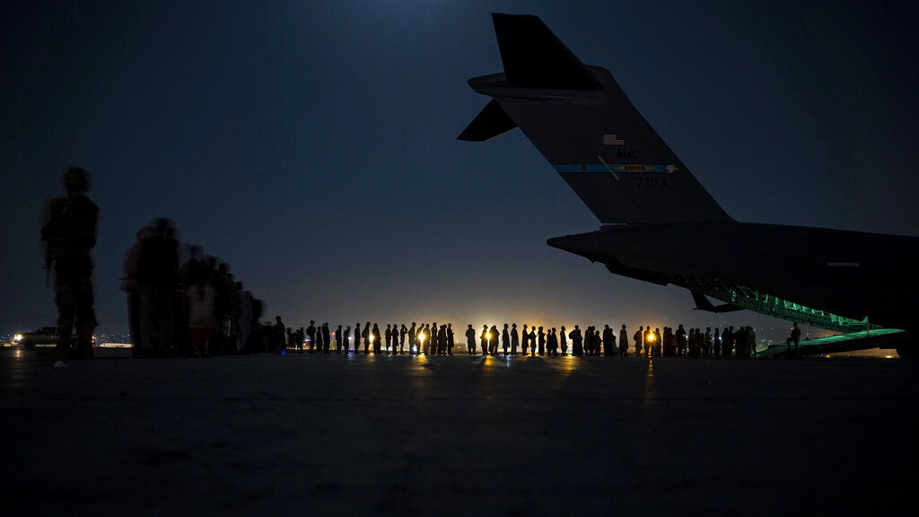 In this image provided by the U.S. Air Force, U.S. Air Force aircrew, assigned to the 816th Expeditionary Airlift Squadron, prepare to load qualified evacuees aboard a U.S. Air Force C-17 Globemaster III aircraft in support of the Afghanistan evacuation at Hamid Karzai International Airport, Kabul, Afghanistan, Saturday, Aug. 21, 2021. (Senior Airman Taylor Crul/U.S. Air Force via AP)