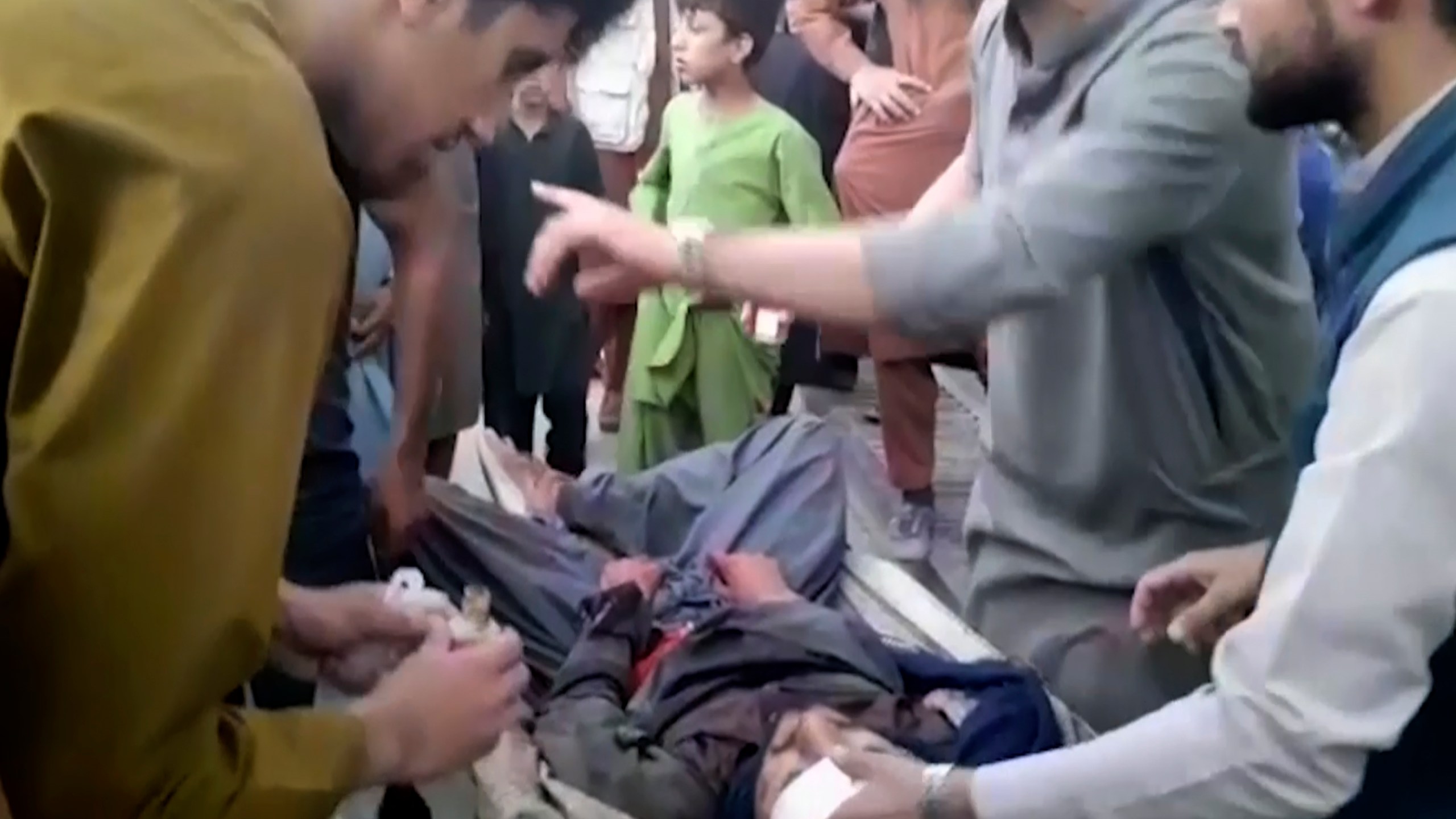 In this frame grab from video, people attend to a wounded man near the site of a deadly explosion outside the airport in Kabul, Afghanistan, Thursday, Aug. 26, 2021. Two suicide bombers and gunmen have targeted crowds massing near the Kabul airport, in the waning days of a massive airlift that has drawn thousands of people seeking to flee the Taliban takeover of Afghanistan. (AP Photo)