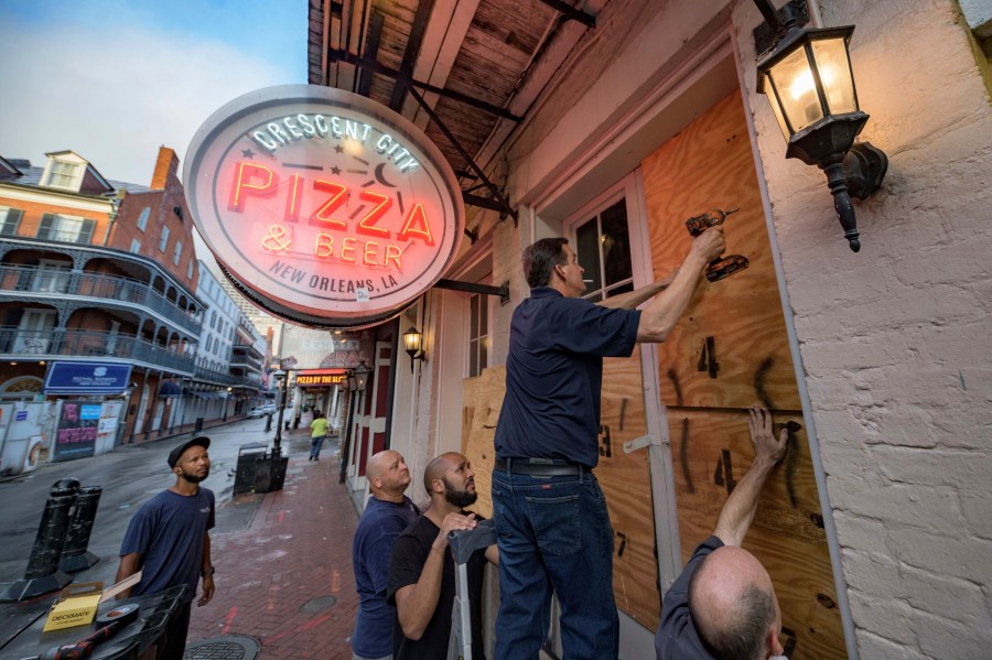 Michael Richard of Creole Cuisine Restaurant Concepts boards up Crescent City Pizza on Bourbon Street in the French Quarter before landfall of Hurricane Ida in New Orleans, Saturday, Aug. 28, 2021. Richard said the group is planning to board up and protect 34 restaurants owned by the company for the storm. (AP Photo/Matthew Hinton)