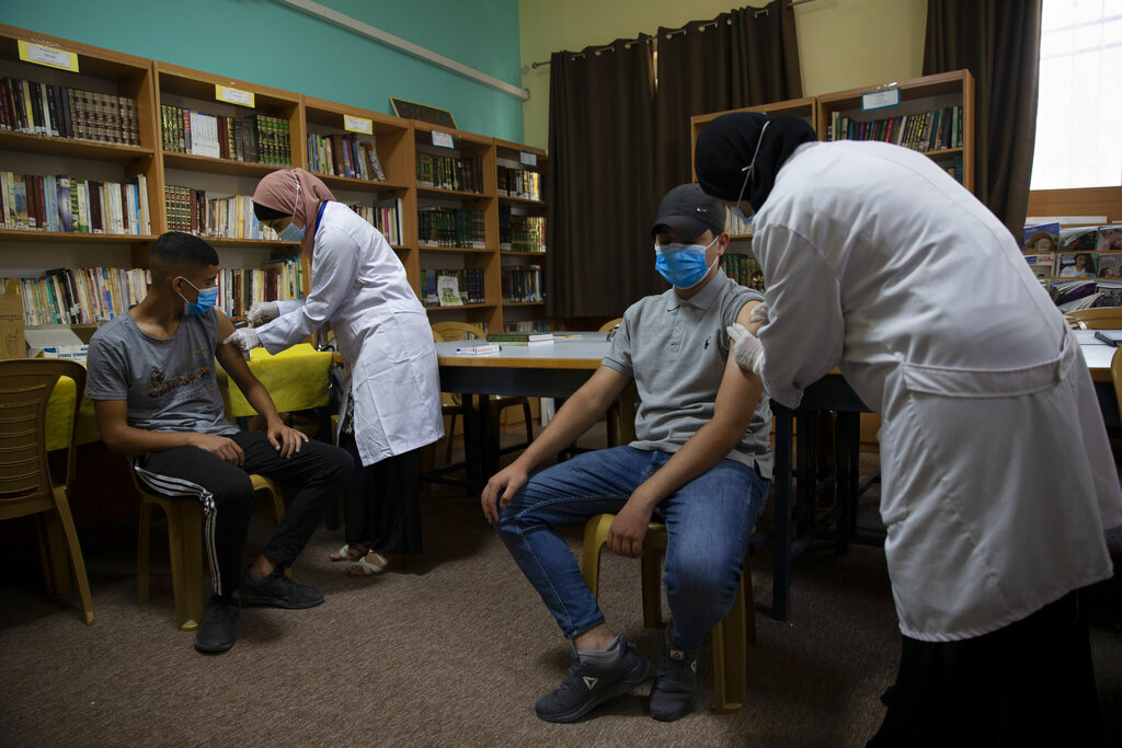 Health workers administer Moderna COVID-19 vaccines to Palestinian students during a back to school vaccination campaign, in the West Bank city of Ramallah, Monday, Aug. 30, 2021. (AP Photo/Majdi Mohammed)