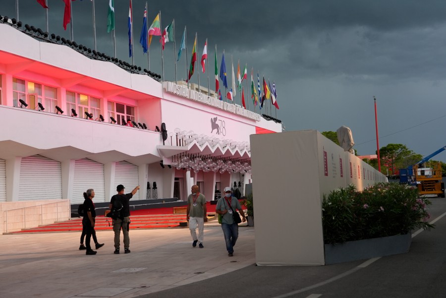 Workers walk by a wall hiding the red carpet of the 78th edition of the Venice Film Festival from the view of the public at the Venice Lido, Italy on Aug. 30, 2021. (Domenico Stinellis/Associated Press)