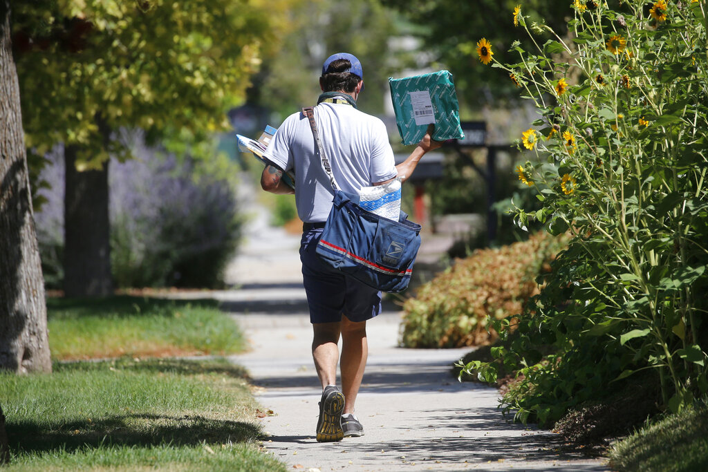 In this Aug. 17, 2020, file photo, a United States Postal Service carrier delivers mail to homes in Salt Lake City. (AP Photo/Rick Bowmer, File)