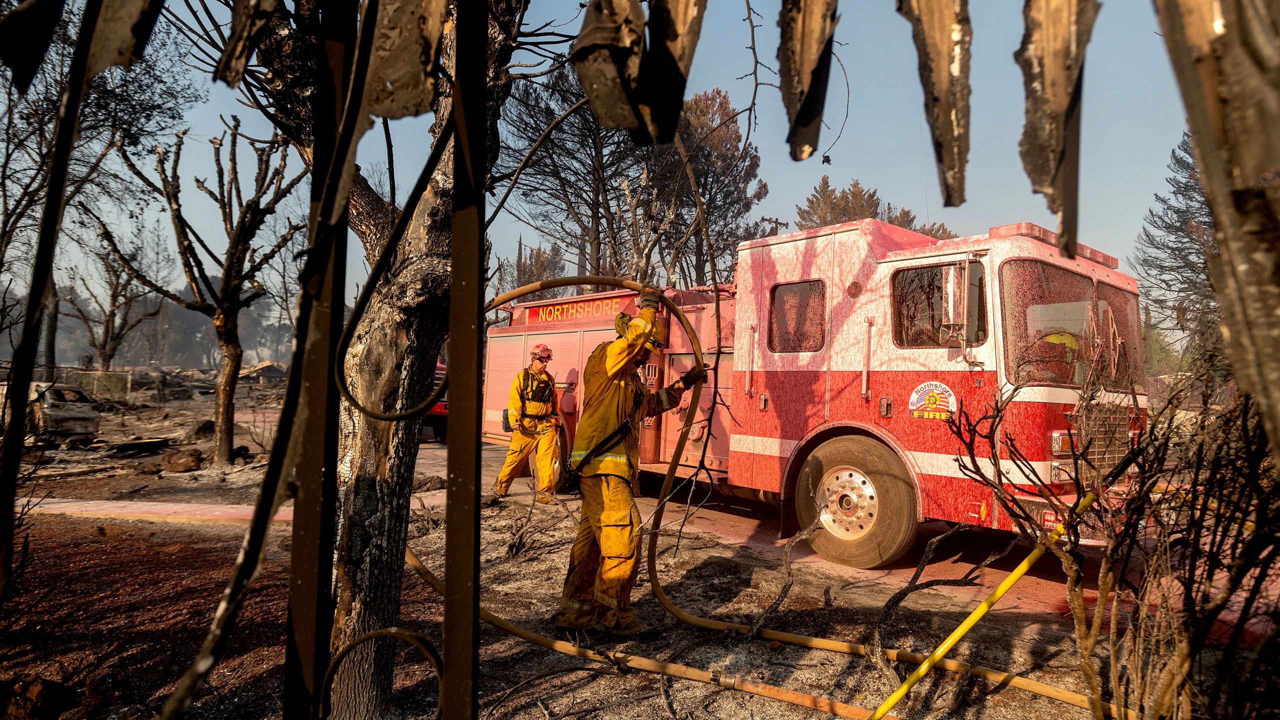 Firefighters mop up at Cache Creek Mobile Home Estates where the Cache Fire leveled dozens of residences on Wednesday, Aug. 18, 2021, in Clearlake, Calif. (AP Photo/Noah Berger)