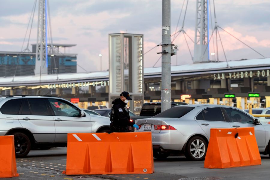 A Customs and Border Protection agent wears a face mask as he walks near cars lining up to cross to the United States at San Ysidro port of entry on March 21, 2020. (GUILLERMO ARIAS/AFP via Getty Images)