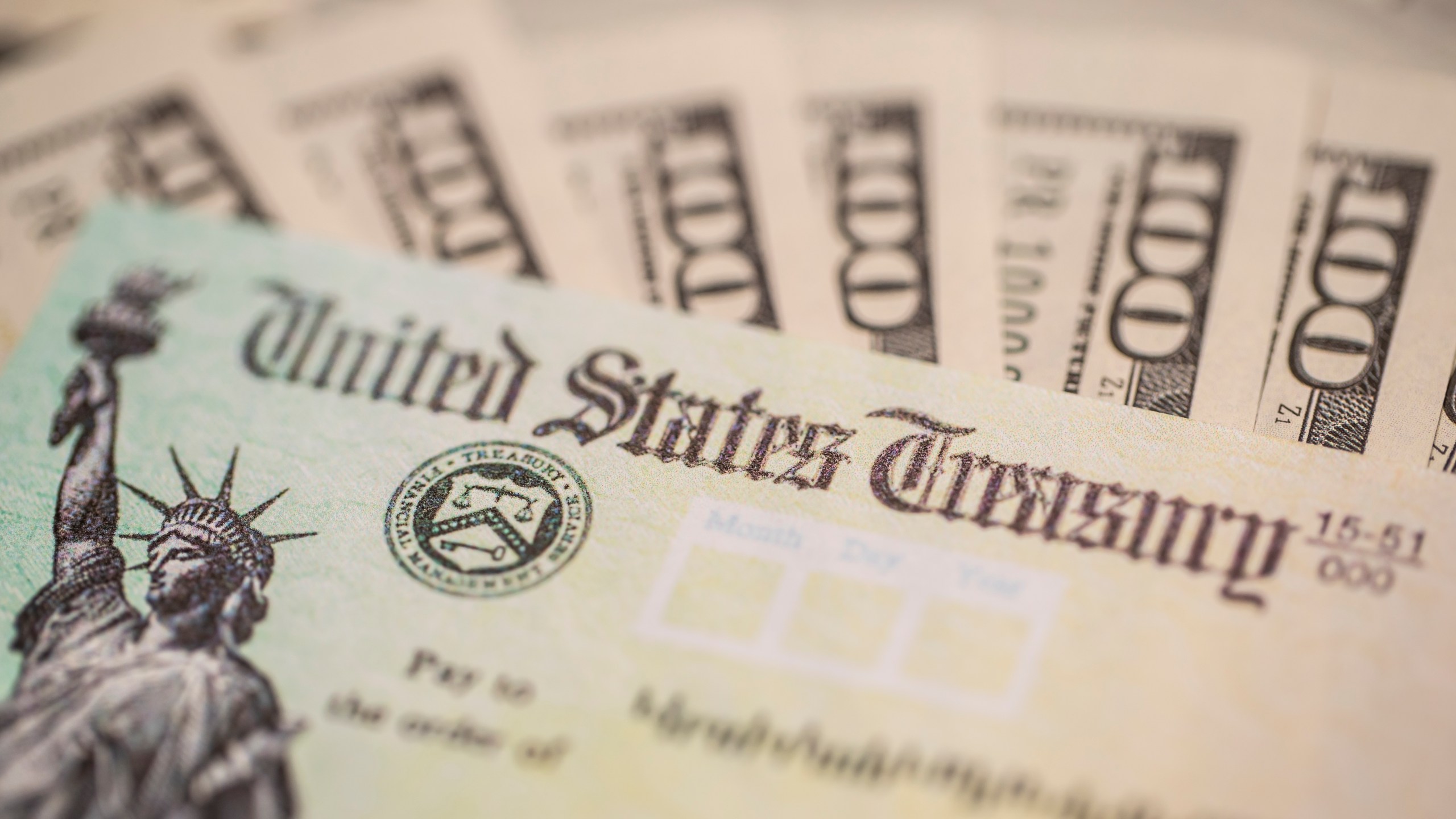 A U.S. Treasury check and $100 bills are seen in a file photo. (iStock/Getty Images Plus)