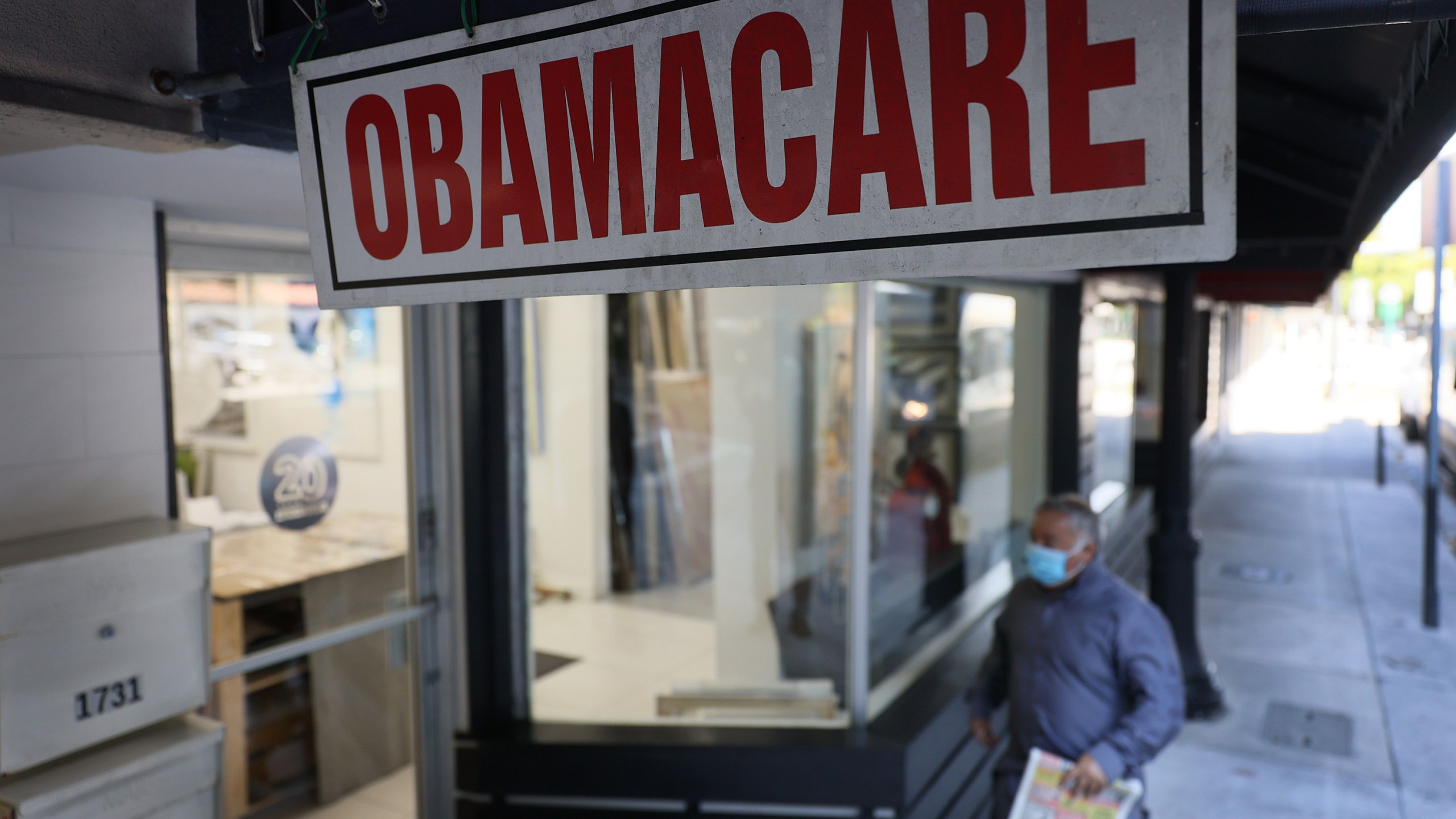 A pedestrian walks past an insurance agency offering plans under the Affordable Care Act on Jan. 28, 2021 in Miami, Florida. (Joe Raedle/Getty Images)