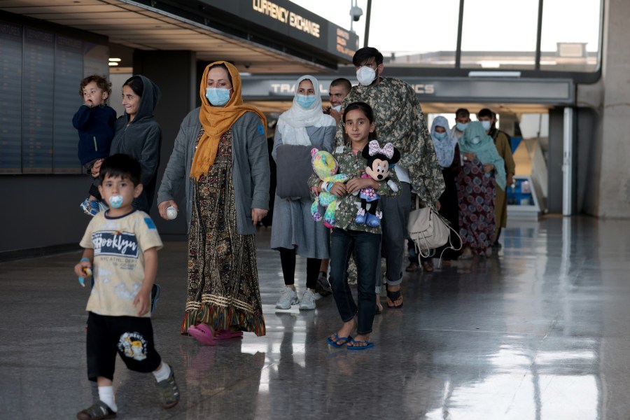 A family evacuated from Afghanistan is led through the arrival terminal at the Dulles International Airport to board a bus that will take them to a refugee processing center on Aug. 25, 2021 in Dulles, Virginia. (Anna Moneymaker/Getty Images)